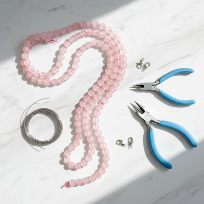 Pink rose quartz 8mm bead strands on white marble with jewellery-making tools