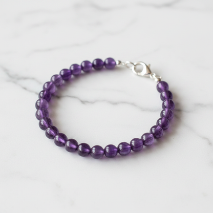 Finished bracelet made from purple amethyst 6mm beads with silver lobster clasp on white marble