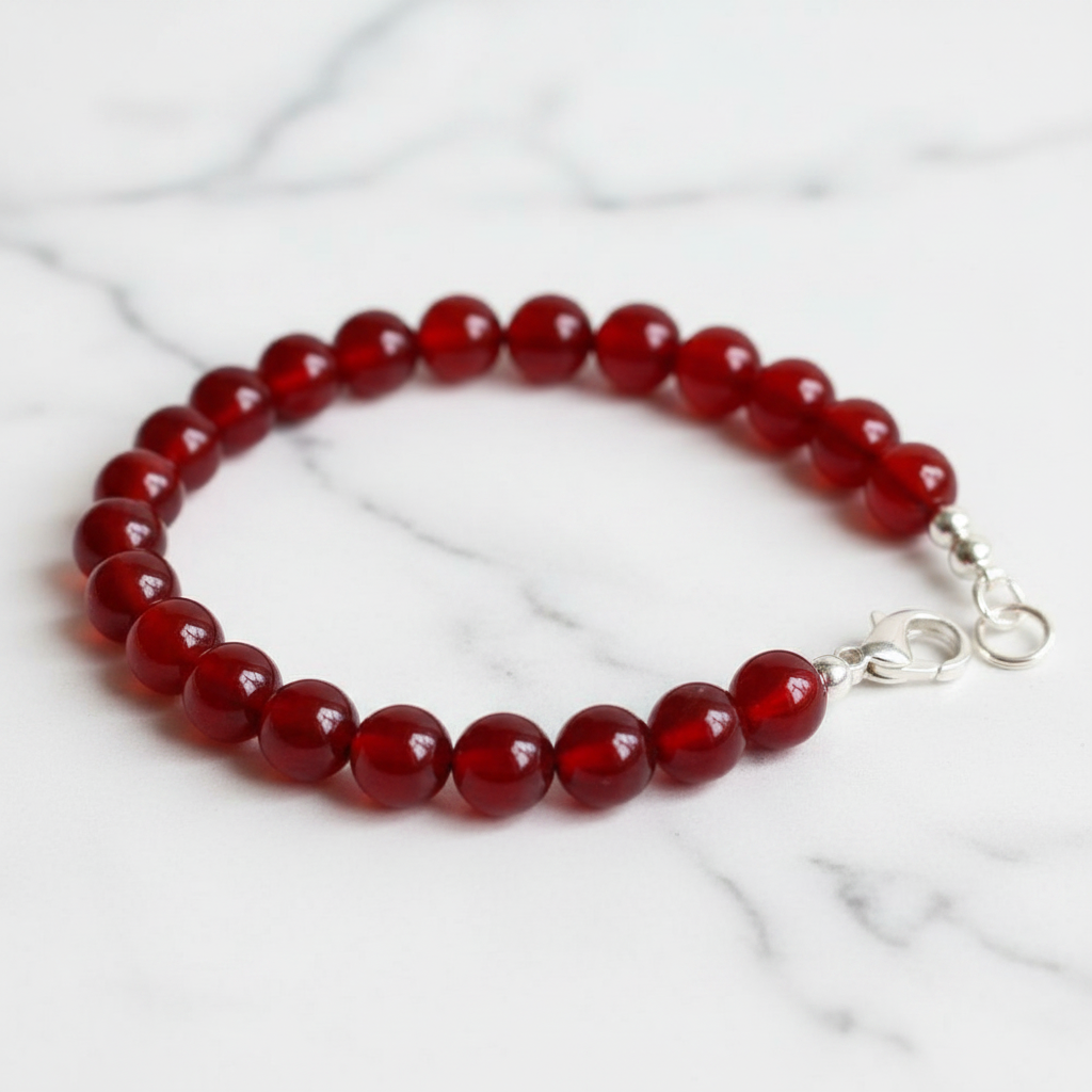 Finished bracelet made from red carnelian 6mm beads with silver lobster clasp on white marble
