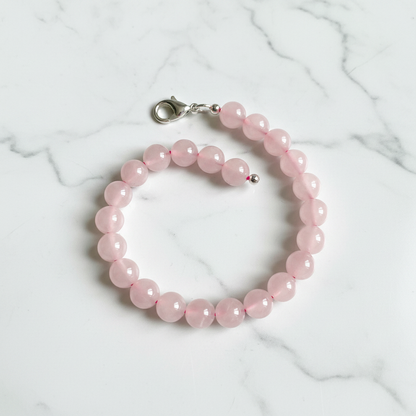 Finished bracelet made from pink rose quartz 8mm beads with silver lobster clasp on white marble