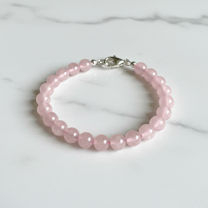 Finished bracelet made from pink rose quartz 6mm beads with silver lobster clasp on white marble